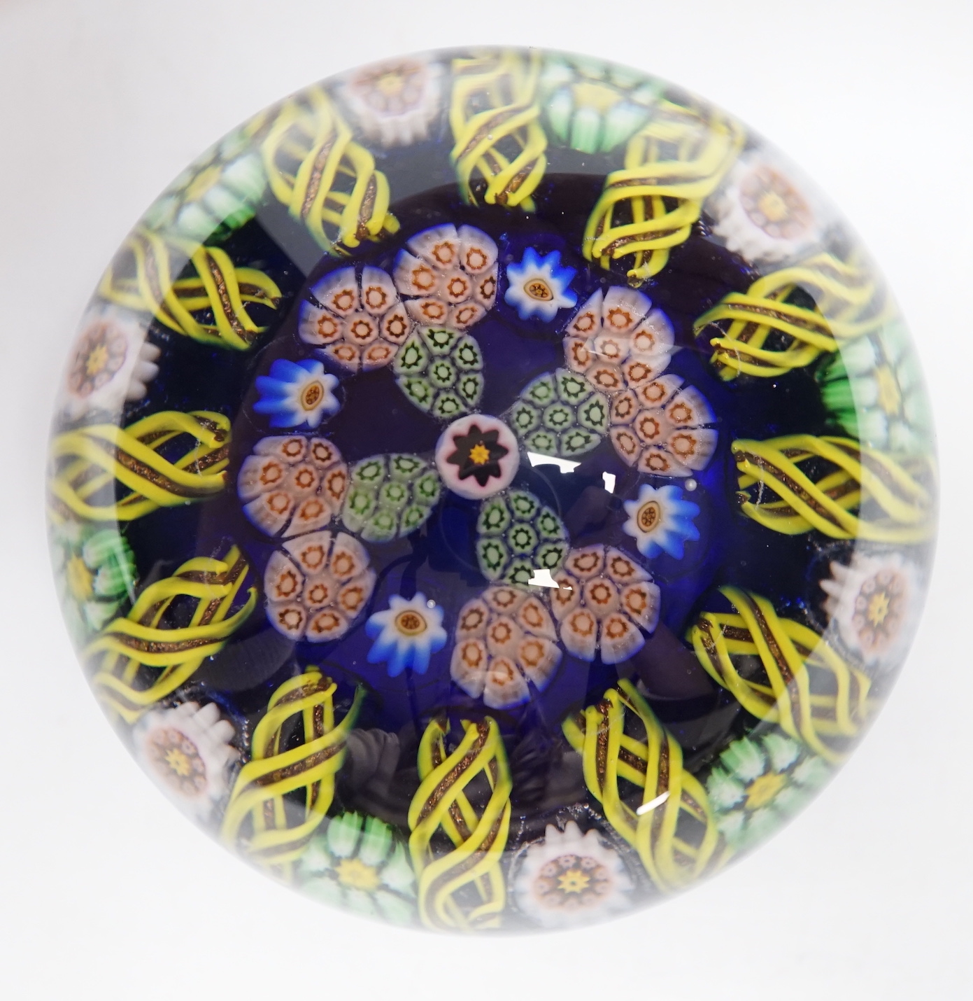 A Paul Ysart millefiori glass paperweight, pre-war Moncrieff period, with central complex canes within a border of aventurine and latticino spokes, transparent blue ground, rough pontil, 7.5cm